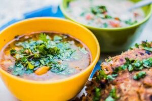 A bowl of red curry with a colorful assortment of vegetables.