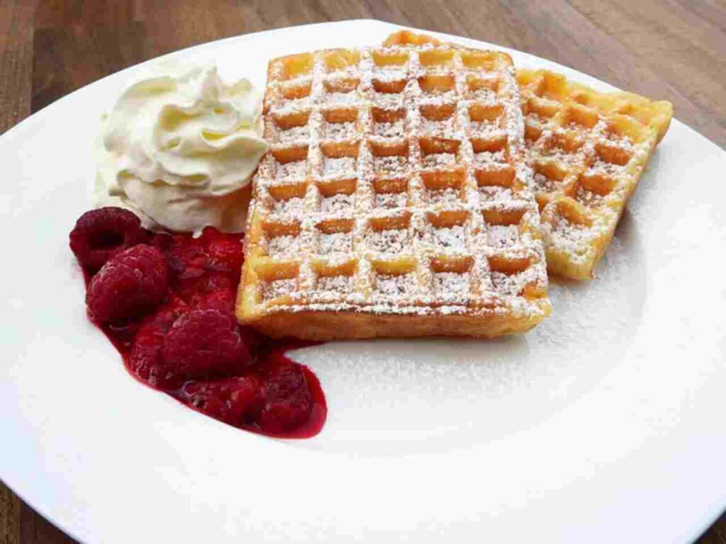 Stack of golden-brown homemade waffles topped with various delicious toppings.