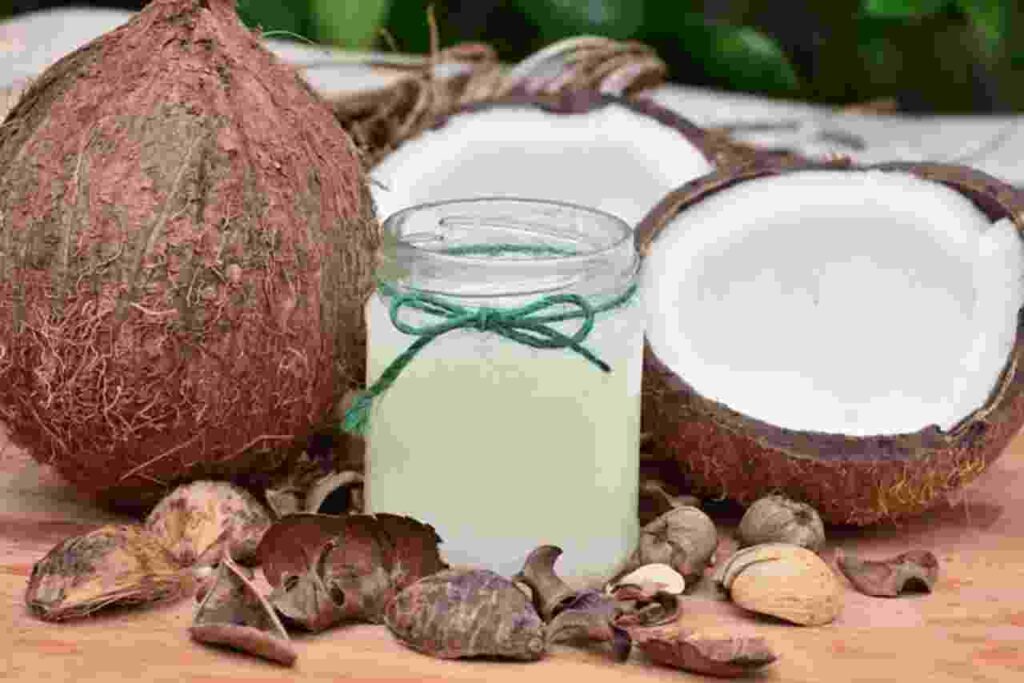 A glass of refreshing coconut water surrounded by tropical fruits and green leaves.