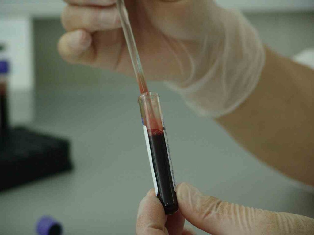 An illustration of a red ribbon symbolizing blood cancer awareness against a backdrop of cells.