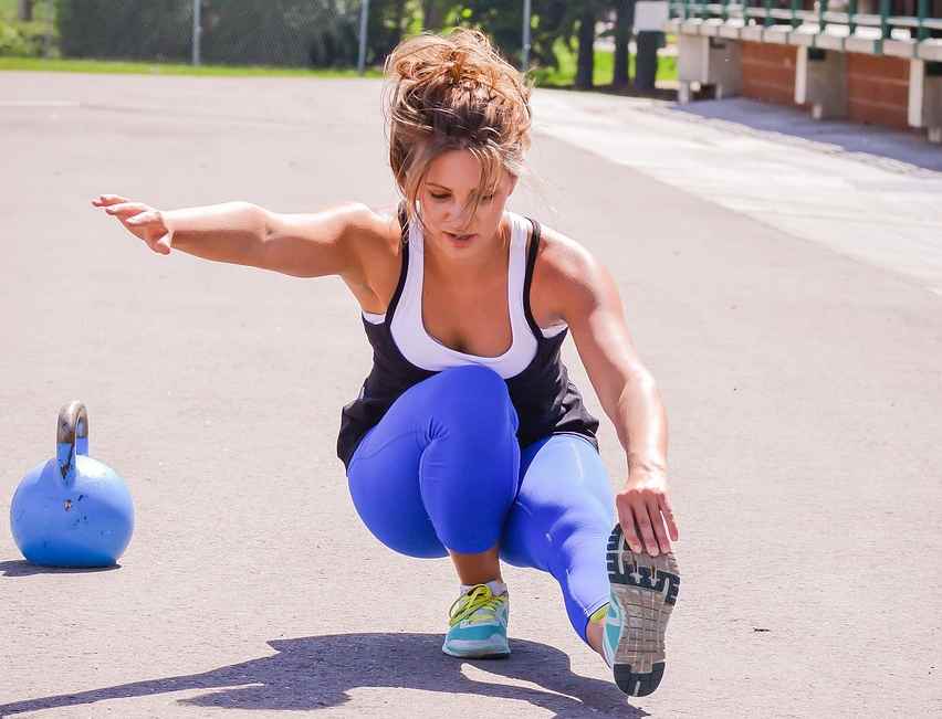 A woman performing a squat exercise with a barbell, focusing on building strong legs through targeted workouts.