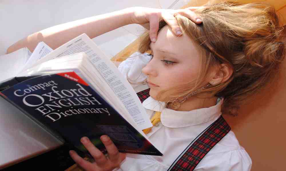 Student with textbooks and laptop, preparing for exams a week in advance.