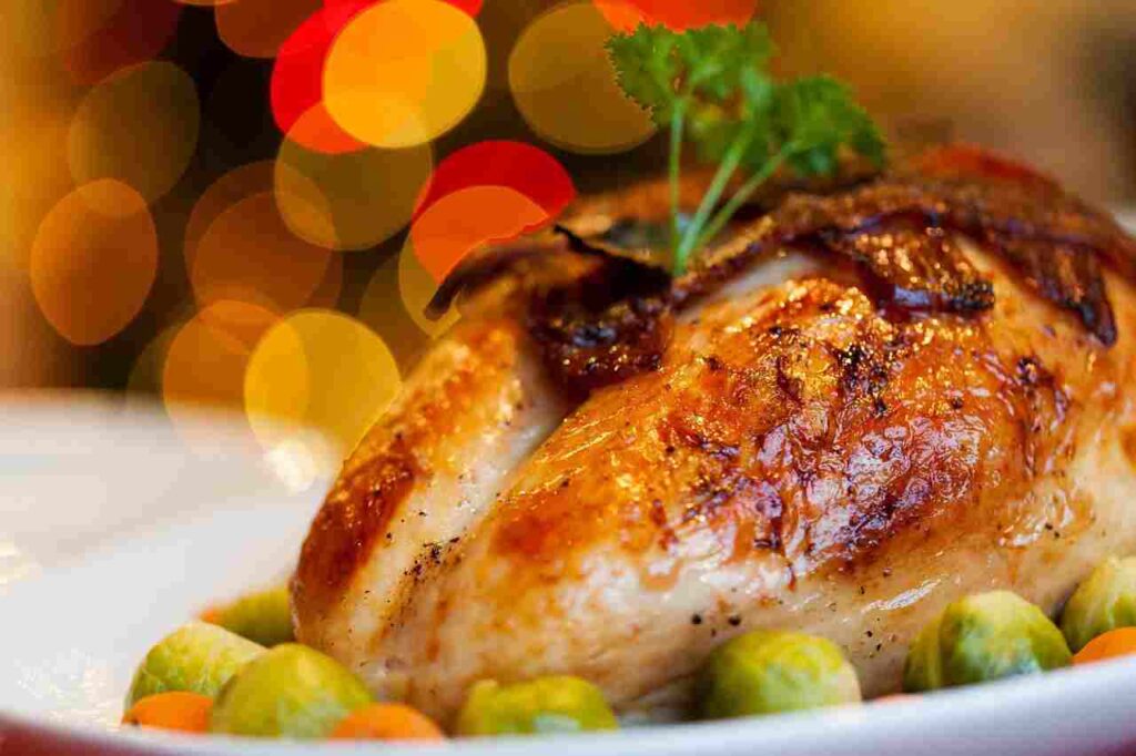 Golden-brown roasted Thanksgiving turkey with a meat thermometer beside it.