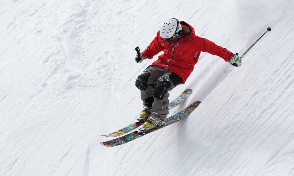 Person skiing down a snow-covered slope with mountains in the background.
