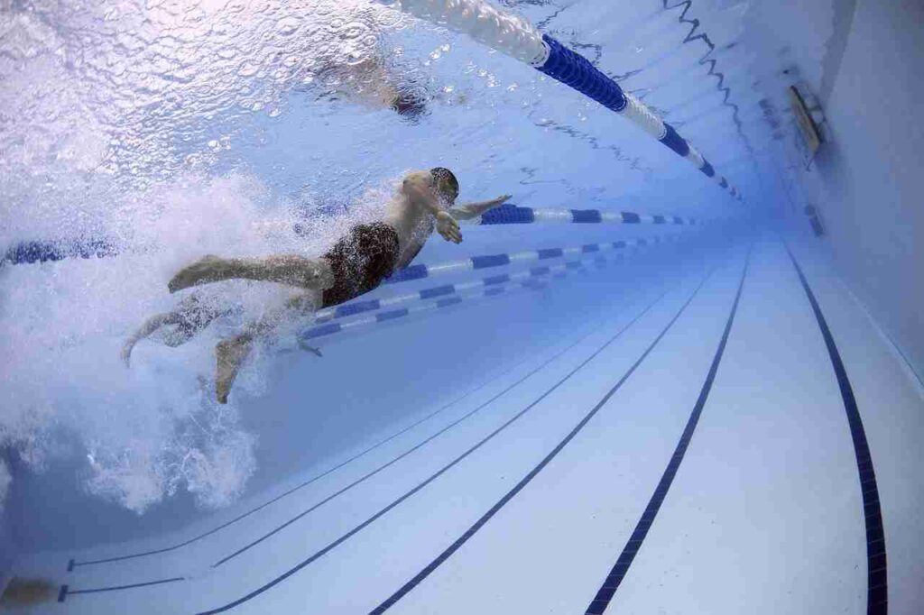 Person swimming in a pool with proper form, wearing swim goggles and cap.