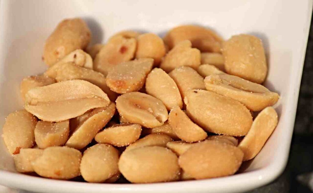 A close-up image of golden, freshly roasted peanuts on a baking sheet.