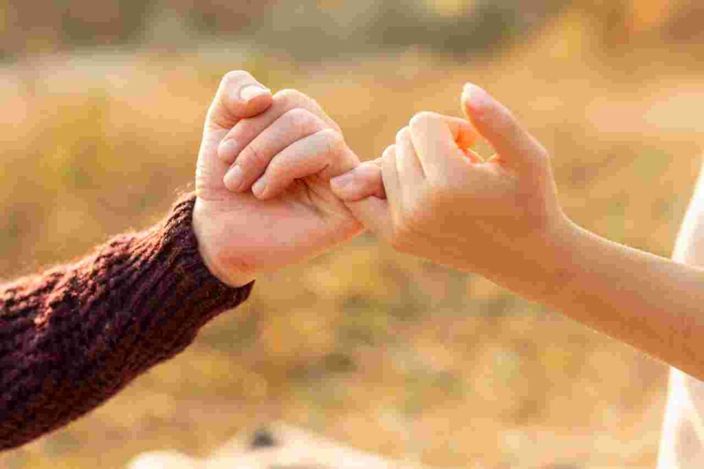 "Two pinkie fingers intertwined in a promise gesture, symbolizing trust and commitment."